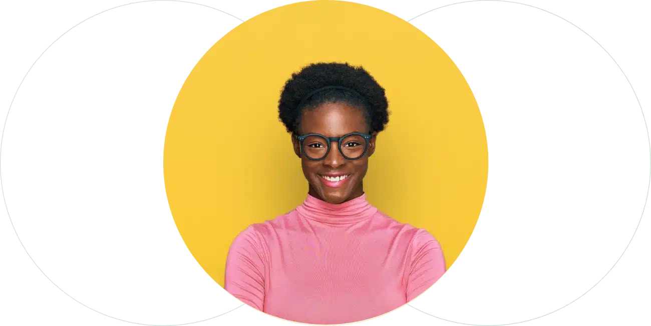 A person with short curly hair, wearing glasses and a pink turtleneck sweater, smiles confidently against a bright yellow background, perfect for a hiring assessment profile.