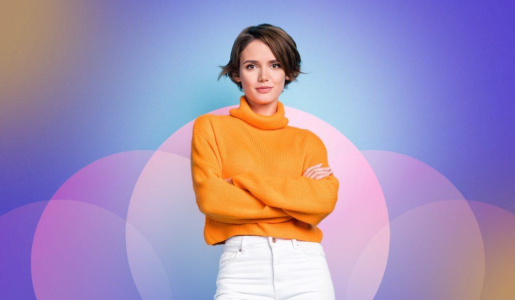 A person with short hair, embodying the confidence of first-line managers, is wearing an orange turtleneck sweater and white pants, standing with their arms crossed. The background features a colorful gradient with circular shapes.